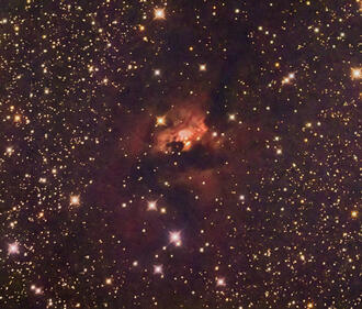 an image of a dark nebula with large gold and orange clouds and yellow stars